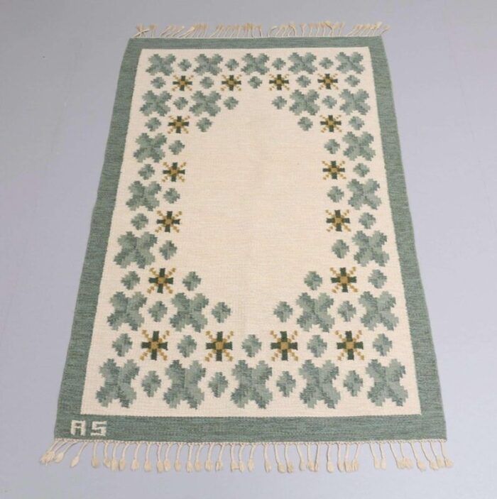 swedish flat weave rug in soft green tones on cream background 1