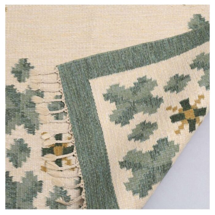 swedish flat weave rug in soft green tones on cream background 3